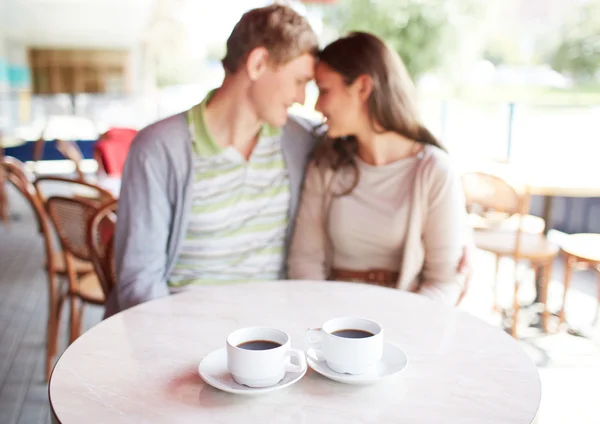 Dos tazas de café en la mesa con pareja romántica —  Fotos de Stock