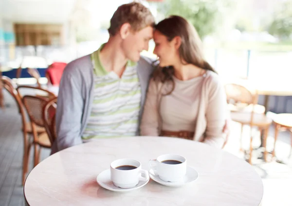 Dos tazas de café en la mesa con pareja romántica — Foto de Stock