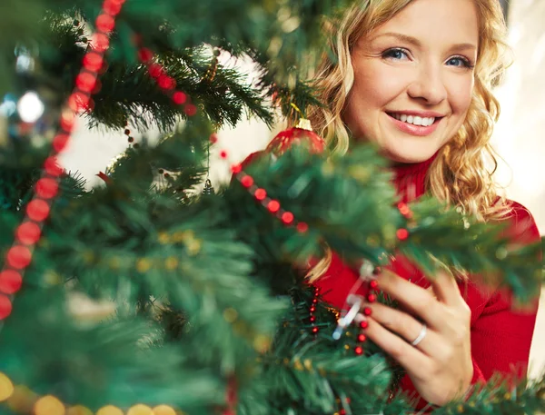 Glückliche Frau schaut aus geschmücktem Tannenbaum Stockbild