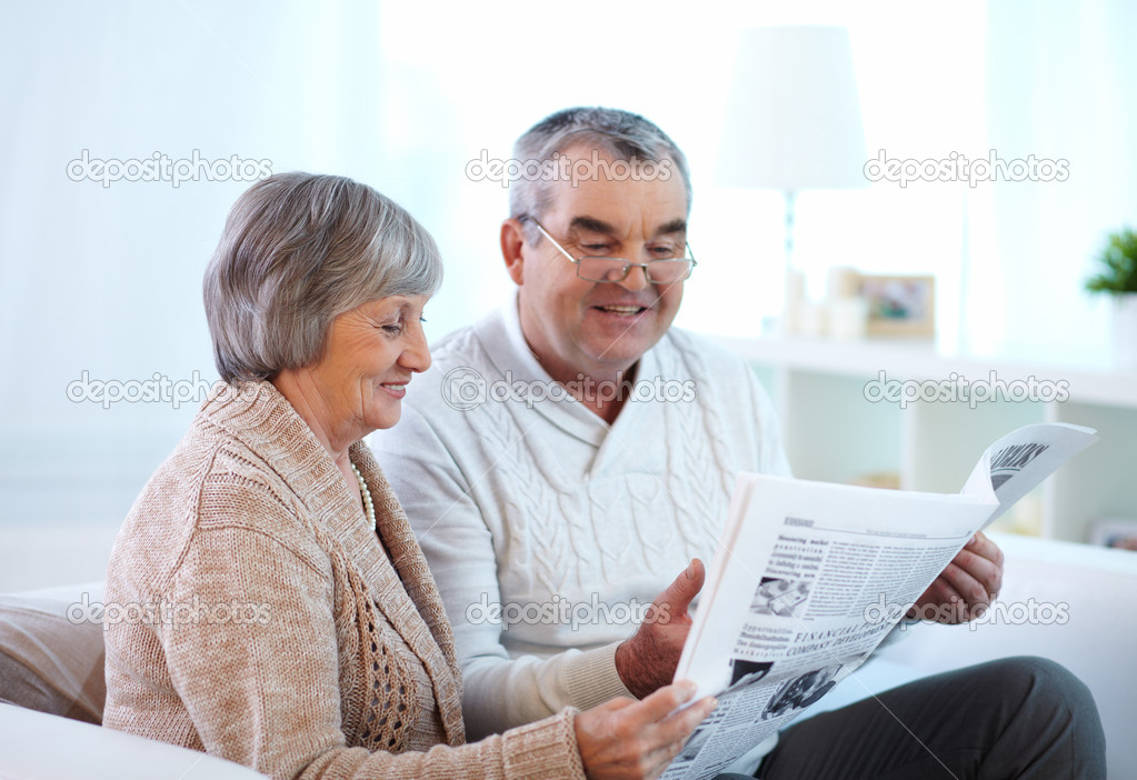 Mature couple reading newspaper together