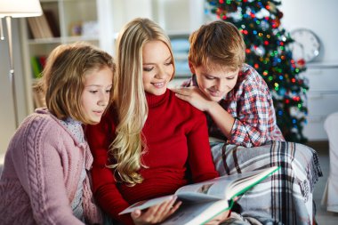 kadın ve onun iki çocuğu Noel akşamı kitap okuma