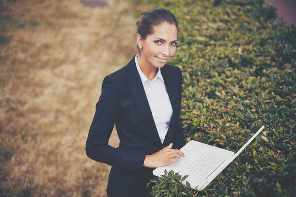 Businesswoman with laptop networking in park — Stock Photo, Image