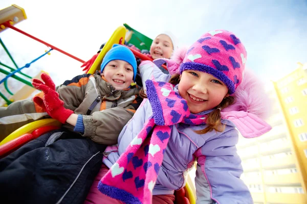 Счастливые друзья веселятся на детской площадке зимой — стоковое фото
