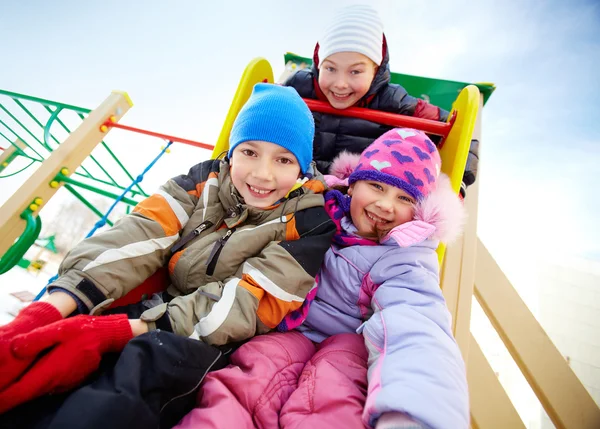 Amigos felizes se divertindo no playground no inverno — Fotografia de Stock