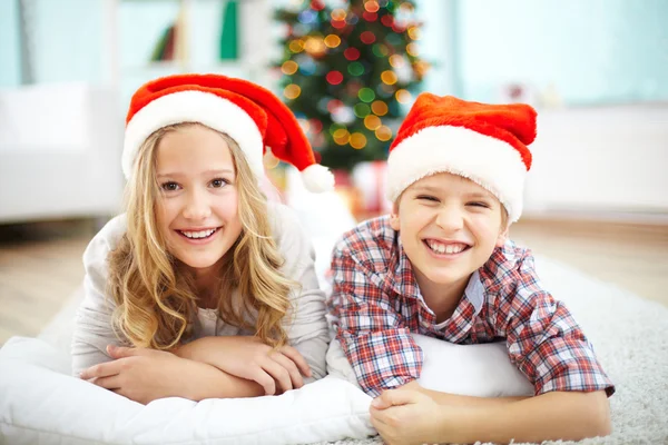 Szczęśliwy rodzeństwo leżącego na podłodze, na Boże Narodzenie wieczorem — Zdjęcie stockowe