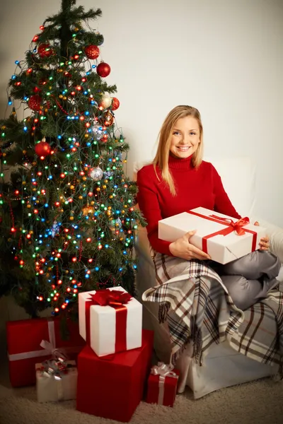 Menina sorridente com caixa de presente vermelha por árvore de xmas decorada — Fotografia de Stock