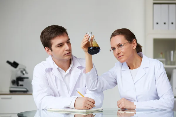 Wetenschappers op zoek naar glas kolf met vloeibare olie — Stockfoto