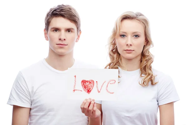 Jovem casal segurando papel com palavra amor — Fotografia de Stock