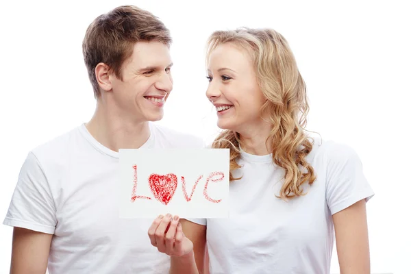 Jovem casal segurando papel com palavra amor — Fotografia de Stock