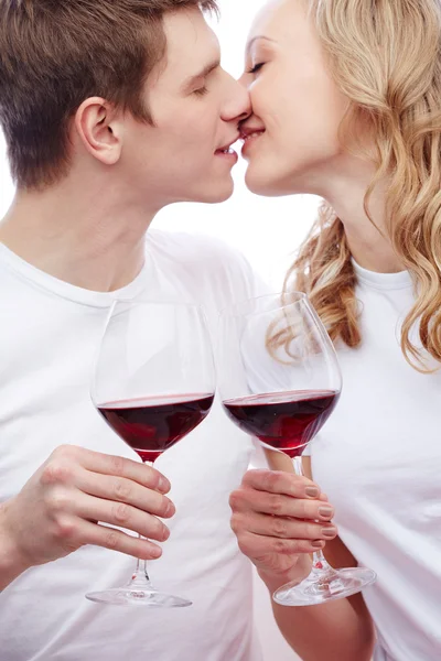 Casal segurando vinho tinto e beijando — Fotografia de Stock