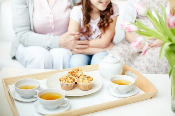 Xícaras de chá e cupcakes na bandeja com a menina — Fotografia de Stock