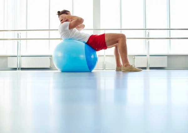 Mann macht körperliche Bewegung auf dem Ball — Stockfoto