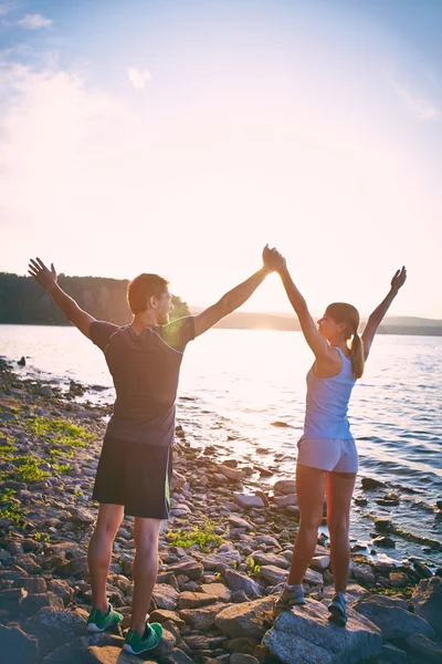 Casal na costa com braços levantados — Fotografia de Stock