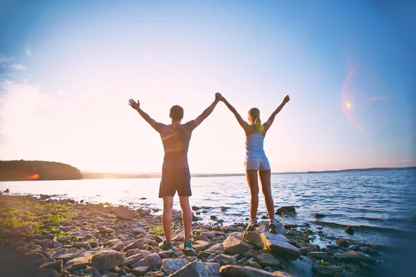 Casal na costa com braços levantados — Fotografia de Stock