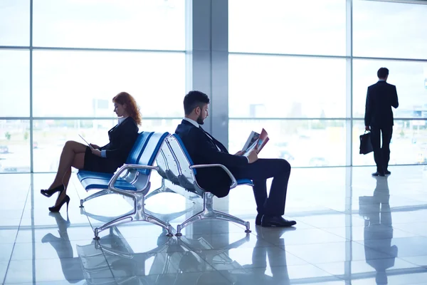 Деловые партнеры читают в аэропорту — стоковое фото