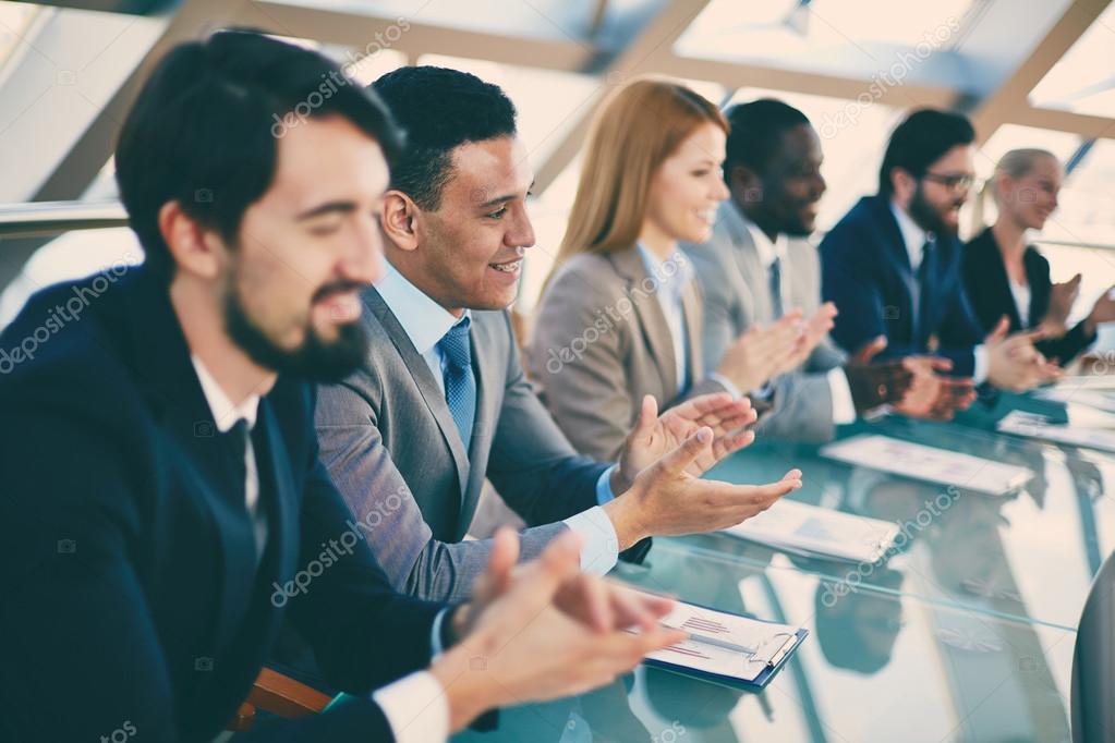 Young business partners applauding to reporter after listening to presentation at seminar