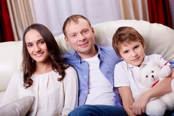 Famille de trois personnes assise à la maison — Photo