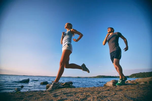 Paar rennt Küste hinunter — Stockfoto
