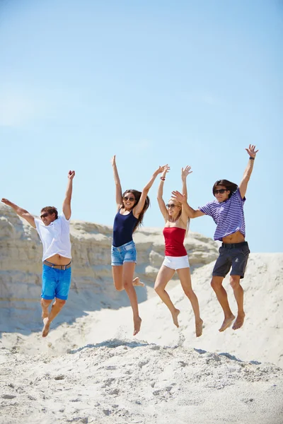 Junge Leute springen über Sandstrand — Stockfoto