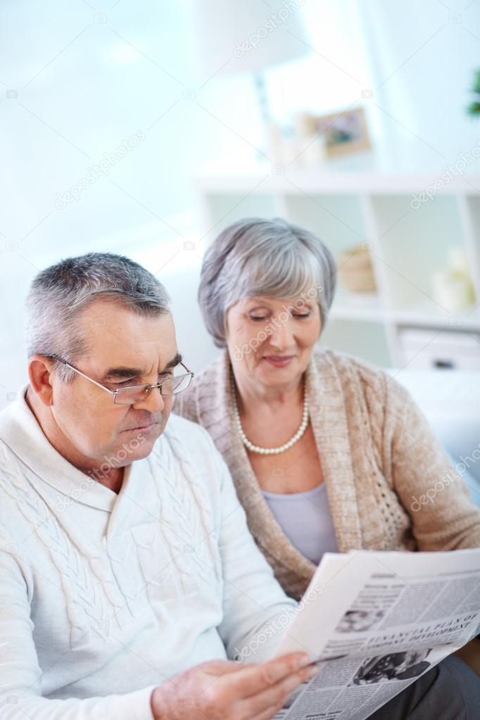 Couple of pensioners reading newspaper