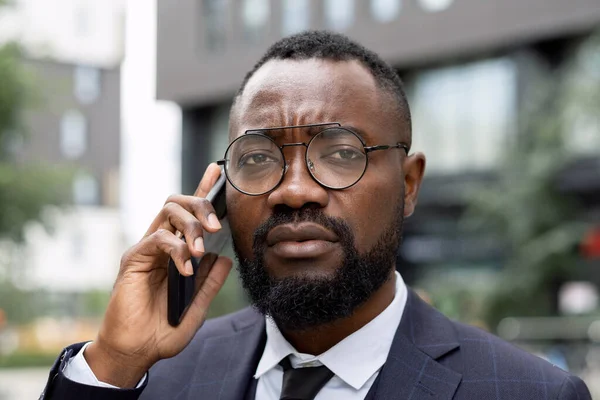 Rosto de jovem homem de negócios elegante em óculos falando ao telefone — Fotografia de Stock
