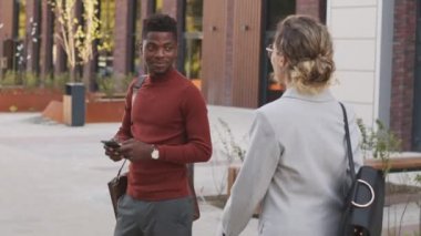 İki çok ırklı iş ortağının açık havada buluşup birbirlerini tokalaşarak selamladıkları havadaki yavaş çekim.