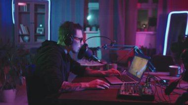 Oturma odasındaki dizüstü bilgisayarda neon ışıklarla aydınlatılan kulaklıklar takan ve mikrofona konuşan genç adamın görüntülerini izliyorum.