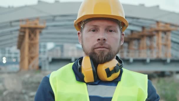 Spårning Närbild Porträtt Skäggiga Manliga Byggarbetare Säkerhetsväst Och Hatt Poserar — Stockvideo