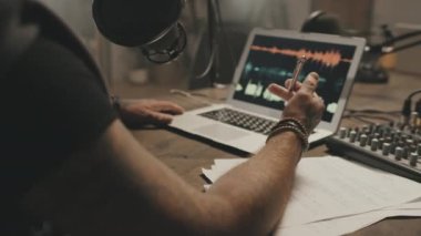 Podcast 'i kaydederken masada oturan ve mikrofona konuşan tanınmayan bir adamın orta bölüm takibi