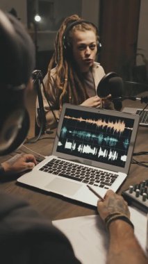Evde ya da stüdyoda oturmuş podcastlarındaki konuyu tartışan genç erkek ve kadının el kamerasıyla çekilmiş görüntüleri.