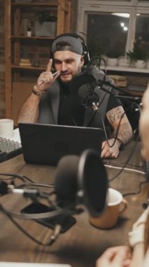 Kulaklıklı bir adam ve kadının evde oturup podcast 'lerini kaydederken el kamerasıyla çekilmiş görüntüleri.