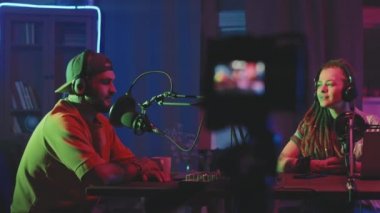 Sakallı bir adamın ve neon ışıklarla aydınlatılmış oturma odasında oturan rastalı bir kadının fotoğrafını çekiyorum.