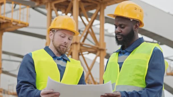 Plano Mediano Ángulo Bajo Ingenieros Caucásicos Afroamericanos Discutiendo Plano Sitio — Vídeo de stock