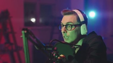 Gözlüklü, kulaklık takan ve podcast 'te mikrofona konuşan bir gencin el kamerası görüntüsü.