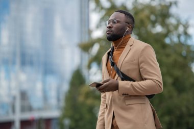 Formalite içinde, kulaklıkla müzik dinleyen genç bir adam.