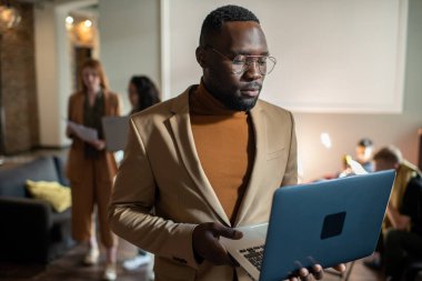 Genç ciddi işadamı elindeki dizüstü bilgisayara bakıyor.