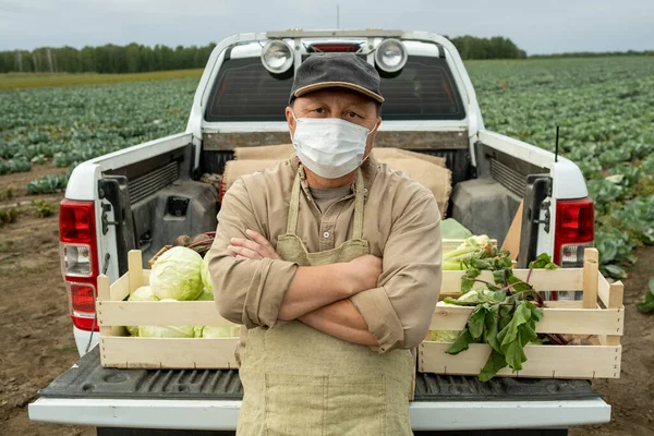 Agricultor contemporáneo en máscara protectora de pie contra el maletero — Foto de Stock