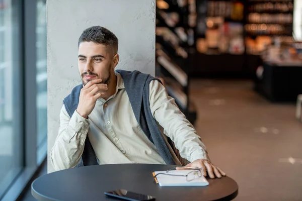 Jovem empresário descansado ou estudante esperando por alguém na livraria — Fotografia de Stock