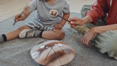 Orta ölçekli, neşeli, genç, sarışın, Asyalı bir kadın ve 3 yaşındaki tatlı oğluyla birlikte halıda oturmuş glukofon oynuyorlar.