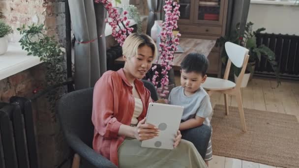 아시아인 어머니와 집에서 디지털 태블릿으로 초상화를 즐기는 느림보 — 비디오