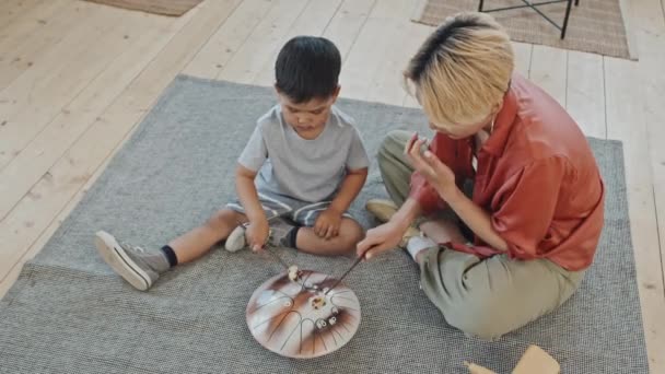 Modern Asyalı Kadın Yaşındaki Oğlunun Evde Oturup Glukofon Çalarken Çekilmiş — Stok video
