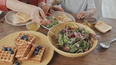 Yüksek açılı, tanınmayan bir kadının yavaş çekimleri. Küçük oğluna bakıyor. Evde birlikte kahvaltı ederken tabağına taze sebze koyuyor.