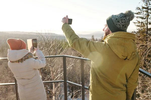 Unga par med smartphones fotografera naturen på vinterdagen — Stockfoto