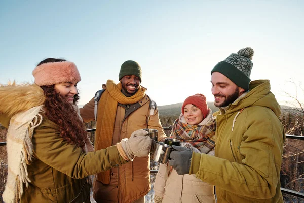 Kışlık giysili genç insanlar sıcak içeceklerle tıkırdıyor. — Stok fotoğraf