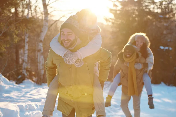 Две счастливые молодые пары в зимней одежде веселятся в солнечный день — стоковое фото