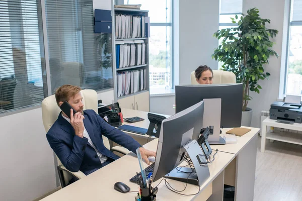 Young businessman speaking on the phone by workplace — Stock Photo, Image