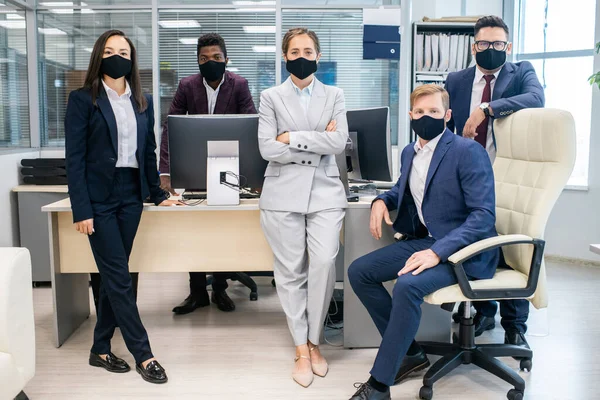 Empresa de jovens funcionários interculturais em máscaras protetoras — Fotografia de Stock