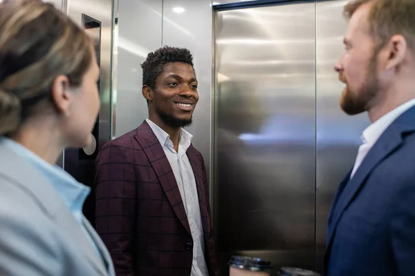 Heureux jeune homme d'affaires africain souriant tout en regardant collègue masculin — Photo