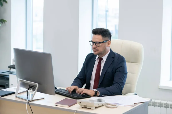 Busy director in elegant suit typing and looking at computer screen — Stock Photo, Image
