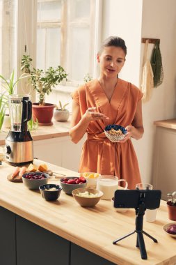 Bir kase kaju fıstıklı genç bayan ev yapımı smoothie tarifini paylaşıyor.